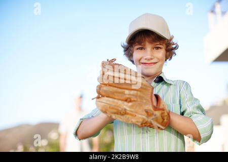 Vous êtes prêt. Portrait court d'un jeune garçon jouant au baseball dans la cour avec son père en arrière-plan. Banque D'Images