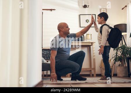 Les élever bien, les féliciter bien. Photo d'un adorable petit garçon donnant à son père un haut cinq avant de partir pour aller à l'école. Banque D'Images