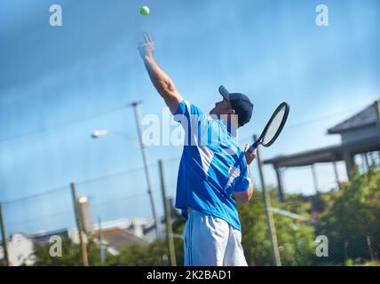 Dynamitage d'un service. Un joueur de tennis masculin lance le ballon dans l'air pour un service - tennis. Banque D'Images