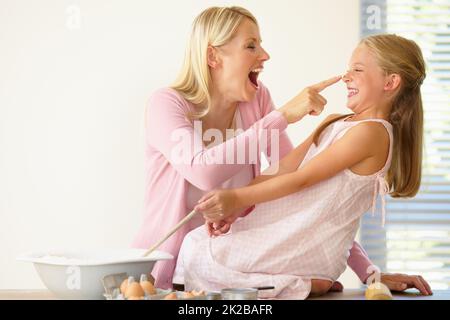 Vous avez. Une mère playa de la farine sur le nez de ses filles tout en cuisant ensemble. Banque D'Images