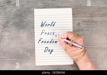 La Journée mondiale de la liberté de la presse se tient sur un papier, la main au stylo est enchaînée, la liberté d'expression, la culture d'annulation, l'écriture de journaliste Banque D'Images