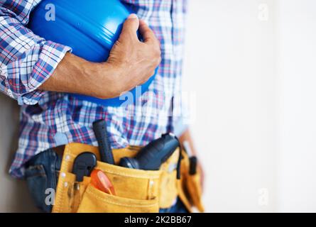 Ouvrier de construction portant un casque de protection. Section centrale de l'ouvrier de construction avec ceinture porte-outils tenant un casque de protection bleu. Banque D'Images