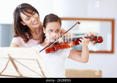 La pratique rend parfaite, ma fille. Une mère aidant sa fille comme elle pratique le violon - CopySpace. Banque D'Images