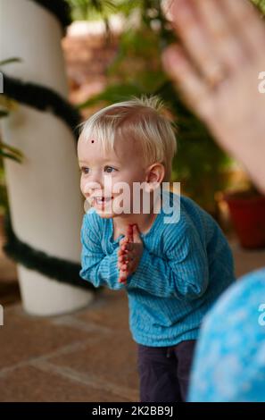 Apprendre les manières de la tradition. Mignon petit garçon orné d'un bindi sur son front, se faussant dans un temple hindou. Banque D'Images