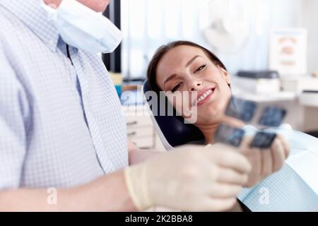 Médecin expliquant la radiographie à la patiente. Portrait d'un dentiste montrant une radiographie à une patiente en clinique. Banque D'Images