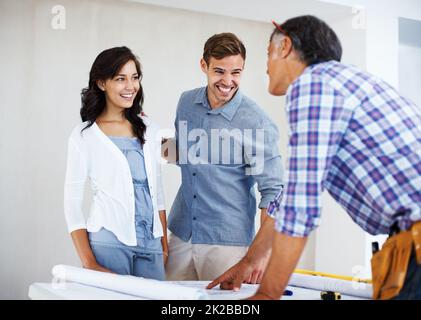 Jeune couple discutant du plan de rénovation de la maison avec l'architecte. Couple heureux discutant du plan de rénovation de la maison avec l'architecte. Banque D'Images