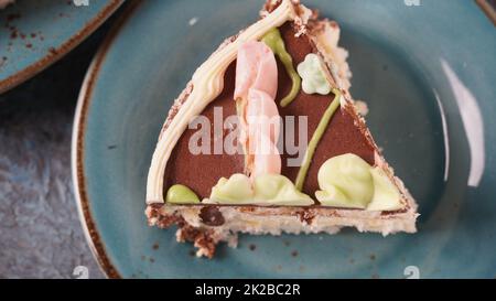 Morceau de gâteau de Kiev à la crème au chocolat et décoré sur une assiette bleue Banque D'Images