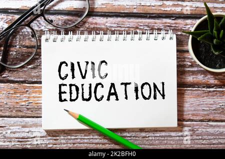 The word CIVIC EDUCATION is written in a white notepad near a white cup of coffee on a light background. Stock Photo