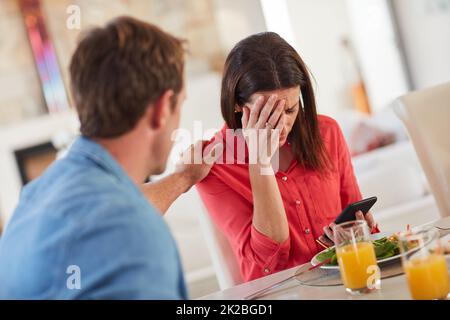 De mauvaises nouvelles peuvent venir à tout moment. Photo d'un homme réconfortant sa femme car elle reçoit de mauvaises nouvelles pendant le déjeuner. Banque D'Images