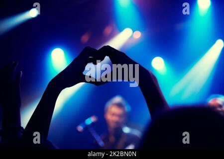 Une jeune personne montrant l'amour et la lumière au groupe sur scène. Ce concert a été créé dans le seul but de cette séance photo, avec 300 modèles et 3 groupes live. Tous les participants à cette séance photo sont sortis du modèle. Banque D'Images