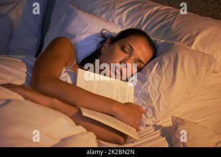 Elle s'est endormie en lisant à nouveau. Photo d'un livre de la tenue d'une jeune femme en sommeil. Banque D'Images