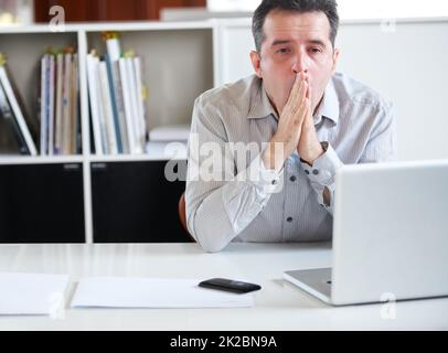 Épuisement sur le lieu de travail. Portrait d'un homme d'affaires à l'aspect stressant, assis devant son ordinateur portable. Banque D'Images