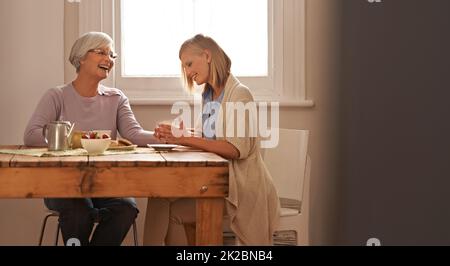 Thé, biscuits et rire - des choses sur lesquelles je peux toujours compter à grands-Noël. Photo courte d'une jeune femme attirante qui visite son gran pour le thé. Banque D'Images