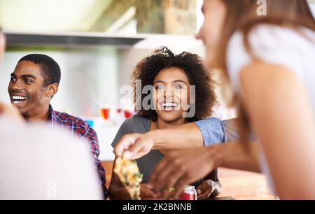 Prendre une tranche de pizza avec des peeps super. Photo d'un groupe d'amis en train de savourer une pizza ensemble. Banque D'Images