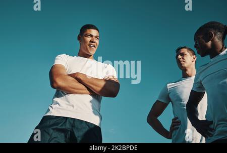 Il est temps de faire une pause. Tir en contre-plongée d'un groupe de jeunes joueurs de rugby qui ont un chat tout en se tenant debout sur le terrain pendant la journée. Banque D'Images