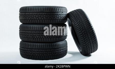 Pile de pneus avec une roue inclinée isolée sur fond blanc Banque D'Images