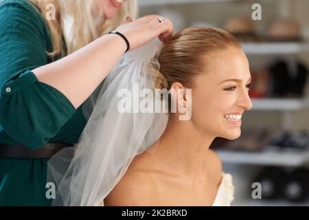 En plaçant ces touches de finition. Une jeune mariée se fait ses cheveux avant le mariage. Banque D'Images