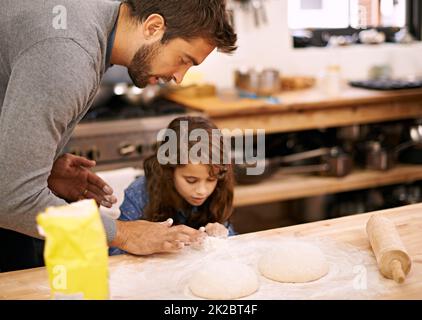 En faisons un tout petit. Photo d'un père et d'une fille travaillant avec de la pâte à pizza dans la cuisine. Banque D'Images