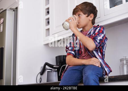 Apprécier son verre de lait quotidien. Un jeune garçon boit un verre de lait. Banque D'Images