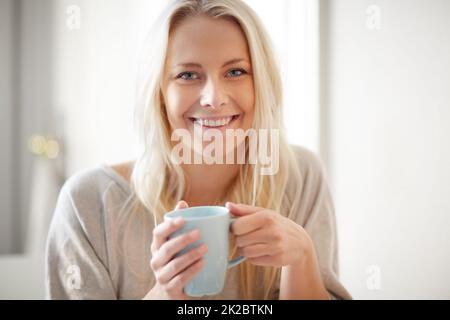 Un coup de pouce le matin. Une jolie jeune femme savourant une tasse de café le matin. Banque D'Images