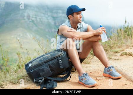 Prendre une pause bien méritée. Jeune randonneur assis et prenant un moment pour se reposer. Banque D'Images