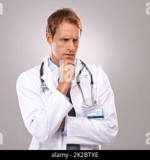 Réfléchir à sa procédure à venir. Photo studio d'un beau médecin qui a l'air attentif. Banque D'Images