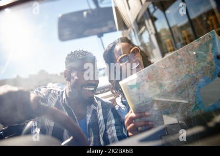 Nous allons trouver un bel endroit pour nous perdre. Photo d'un jeune couple qui lit une carte tout en étant assis dans la voiture. Banque D'Images