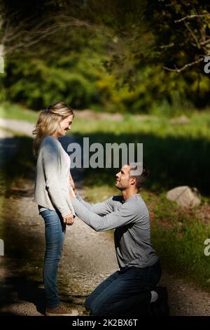 Ils allaient être parents. Photo d'un homme qui s'agenouille et touche son estomac en profitant d'une journée dans le parc. Banque D'Images