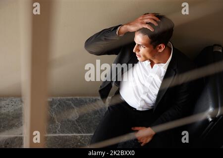 Fatigué de tout ce voyage d'affaires. Photo d'un jeune homme d'affaires épuisé assis sur le sol à côté de ses bagages. Banque D'Images