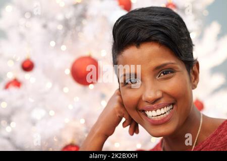 Noël est dans l'air. Portrait d'une belle jeune femme à côté d'un arbre de Noël. Banque D'Images