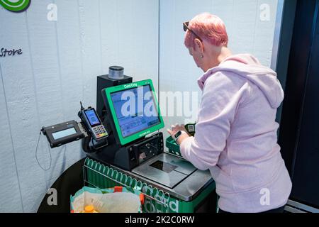 Australian woman, model released, pink hair, using grocery self checkout machine in Sydney supermarket,Australia Stock Photo