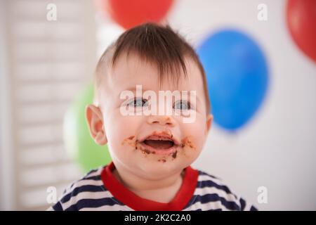 Mmm...cake. Portrait d'un bébé garçon à son anniversaire. Banque D'Images