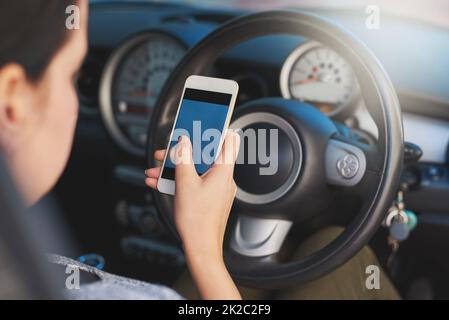 Conduite distraite. Prise de vue d'une femme utilisant un téléphone en conduisant. Banque D'Images