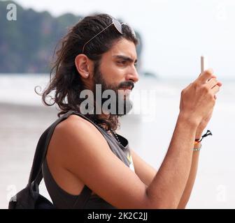 Souvenez-vous de ce moment. Photo d'un jeune homme prenant des photos sur son téléphone à la côte. Banque D'Images