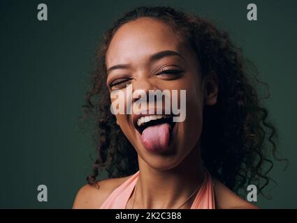 Elle ne partage pas son côté fou avec tout le monde. Portrait court d'une jeune femme attrayante et originale se posant sur un fond vert en studio. Banque D'Images