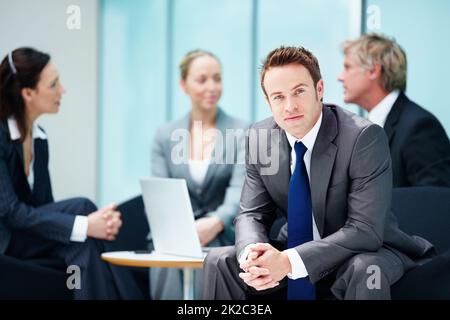 Homme d'affaires confiant avec d'autres cadres. Portrait d'un homme d'affaires confiant avec des cadres discutant en arrière-plan. Banque D'Images