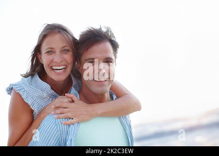 Dévotion et bonheur. Un couple mûr enchantant embrassant à côté de l'espace d'imitation sur la plage. Banque D'Images