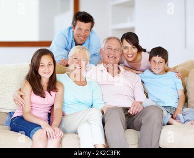 Vivre ensemble - soutien familial. Trois générations de familles assises avec affection sur le canapé-lit. Banque D'Images