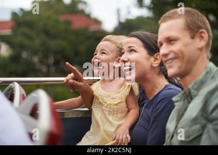 Regardez ça Photo d'une jeune famille assise dans un bus tandis que la mère pointe vers le ciel. Banque D'Images