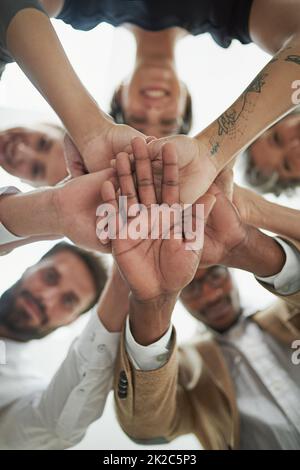 Nous le faisons ensemble ou Pas du tout. Portrait d'un groupe d'hommes d'affaires en bas angle mettant leurs mains dans un tas. Banque D'Images