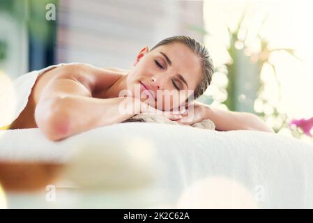 Mon esprit, mon corps et mon âme sont en harmonie. Photo d'une belle jeune femme allongé sur une table de massage au spa de jour. Banque D'Images