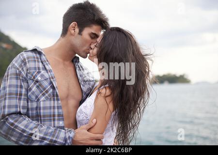 Prendre leur amour dehors. Photo d'un jeune couple intime en profitant d'un baiser au bord de l'eau. Banque D'Images