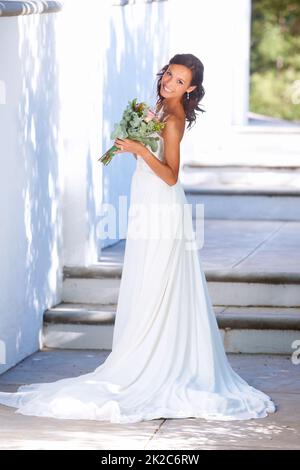 Aimer chaque moment de la vie amoureuse. Une belle jeune mariée debout dehors avec son bouquet. Banque D'Images