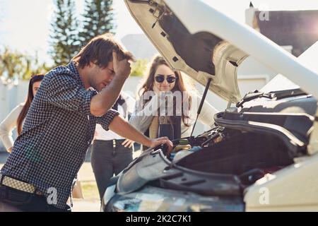 Je ne peux pas m'en assurer. Photo d'un jeune homme regardant sous le capot d'une voiture en panne. Banque D'Images