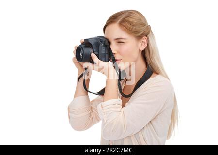 La vie à travers l'objectif. Prise de vue en studio d'une belle jeune femme prenant des photos avec son appareil photo sur fond blanc. Banque D'Images