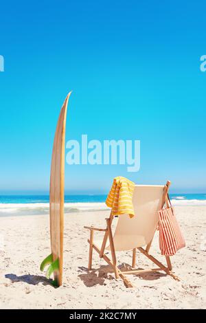 Prêt pour les vagues. Photo d'une chaise longue et d'une planche de surf sur la plage. Banque D'Images