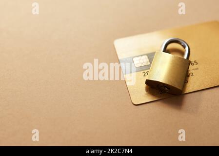 Prenez les bonnes mesures pour réduire vos risques. Studio photo d'une carte de crédit et de verrouiller sur fond marron. Banque D'Images