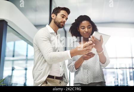 Offrant ses conseils et son soutien. Photo de deux hommes d'affaires discutant de quelque chose sur une tablette numérique. Banque D'Images