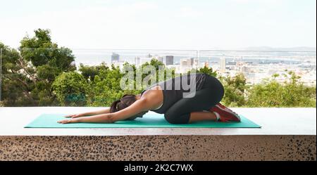 Etirer le stress. Prise de vue en longueur d'une jeune femme sportive faisant du yoga sur un balcon. Banque D'Images