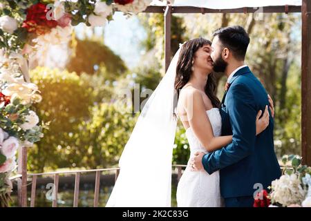 Je suis si heureux de vous embrasser pour le reste de ma vie. Photo courte d'un jeune couple affectueux, jeune et jeune, qui embrasse tout en se tenant debout à l'extérieur le jour de leur mariage. Banque D'Images